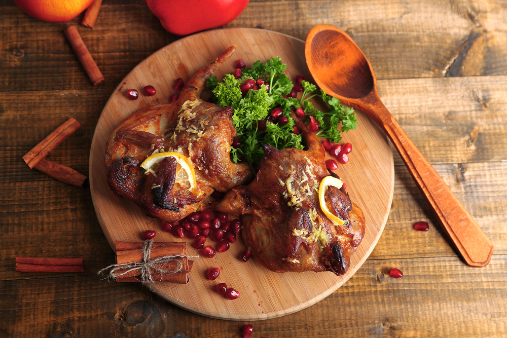 Roasted quails on cutting board, on wooden table background